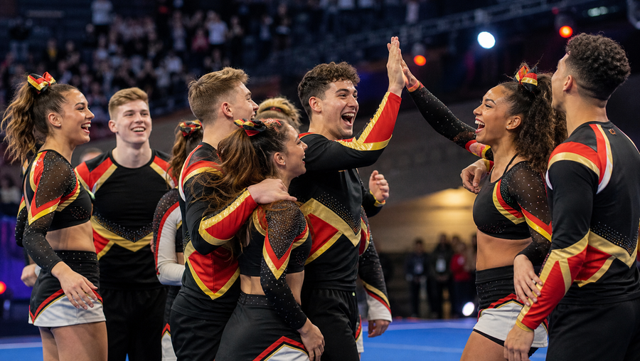 Fiktives Cheer-Team mit schwarz-rot-goldenen Akzenten jubelt nach einem Wettkampf